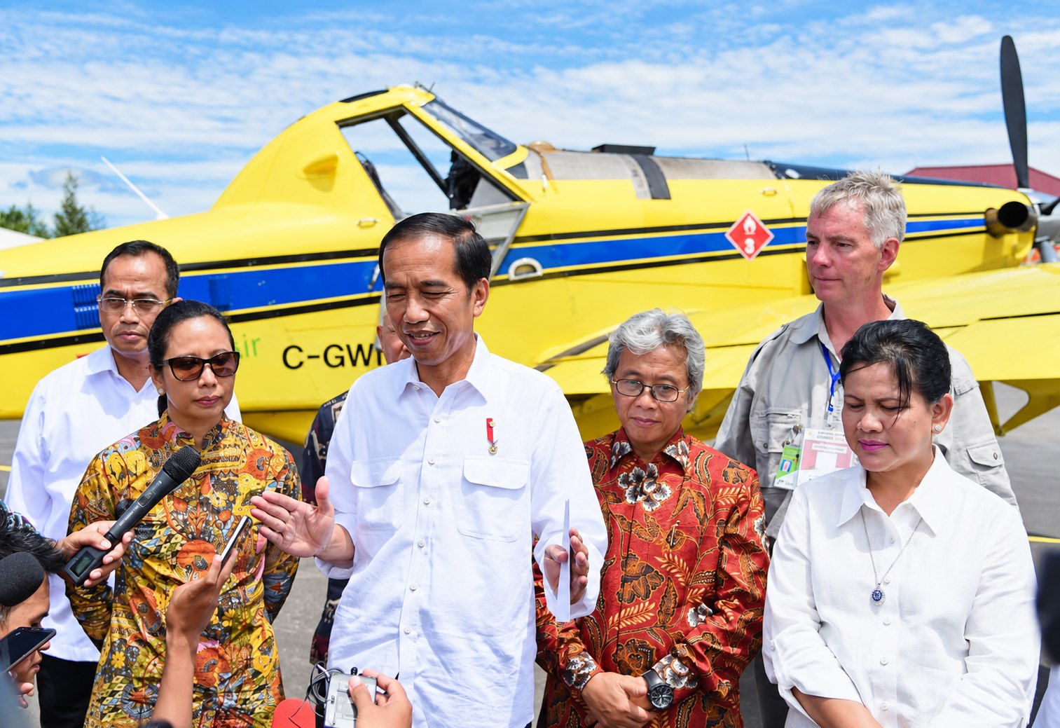 A press gathering in front of a yellow FuelBoss aircraft in Papua