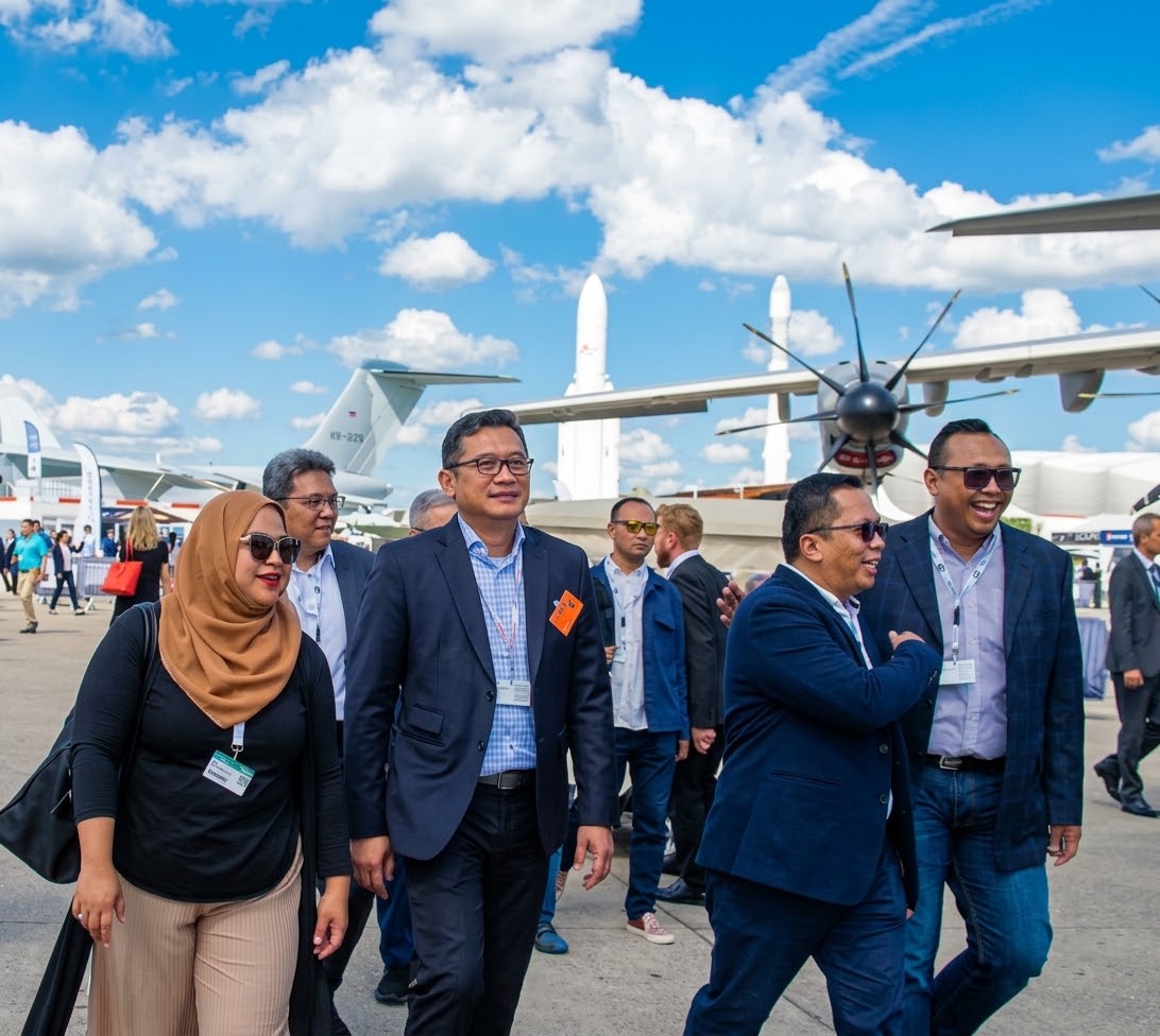 Kevinia Pramono-Rizqi and Muhamad Rizqi with delegates beside aircraft on display at Changi Exhibition Centre
